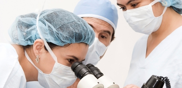 Medical professional looking through a microscope